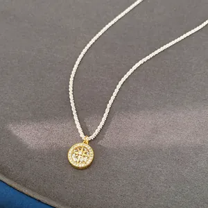 Detailed macro view of a gold north star pendant with zircon on white knotted cord