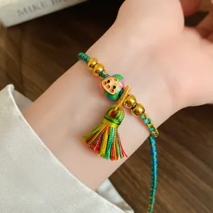 Close-up detail of a colorful handmade braided bracelet with a vibrant silk tassel.