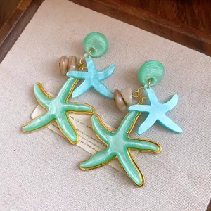 Detail showing mint green and blue resin starfish earrings with elegant gold borders
