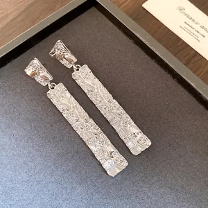 Detailed macro view of silver-colored rectangular earrings with a unique crumpled texture