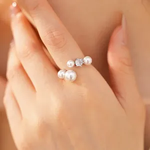 Macro view of a luxury adjustable open ring featuring white pearls and a sparkling zircon stone