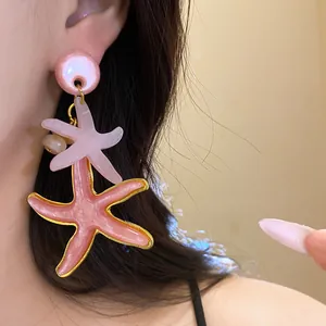 Close-up detail of stylish pink resin starfish drop earring worn on a female ear model
