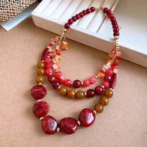 Detail view of a multi-layer beaded necklace featuring red agate and resin stones.