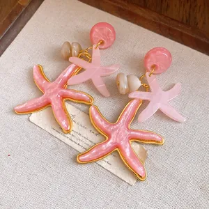 Macro view of pink resin starfish dangle earrings with elegant shell textures