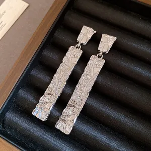 Close-up of silver-tone drop earrings with a unique wrinkled metal texture