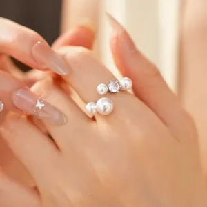 Elegant detail of a silver adjustable ring featuring white pearls and a sparkling zircon stone