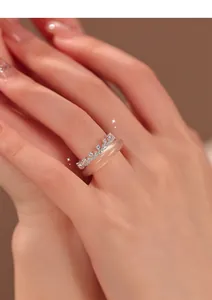 Detailed close-up of elegant crown zircon lace ring with peach resin band on model hand