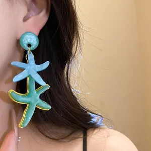 Detailed view of layered resin starfish drop earrings worn by a model in a resort style