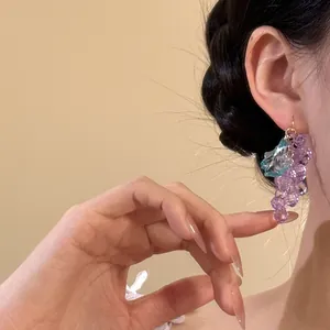 Detaillierte Nahaufnahme von eleganten lila Trauben-Ohrhängern, getragen von einem Modell