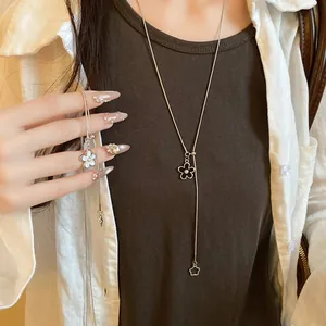 Close-up detail of a silver flower pendant necklace with a pearl center on a model