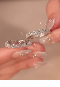 Close-up of elegant silver lace rings with sparkling zircons held between fingers