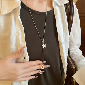 Close-up of an elegant silver-toned pull-out flower pendant necklace worn with a white shirt