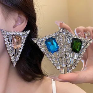 Close-up of geometric triangle rhinestone earrings with colorful square center gemstones.