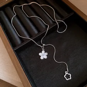 Close-up detail of a silver snake chain necklace featuring elegant pearl flower pendants