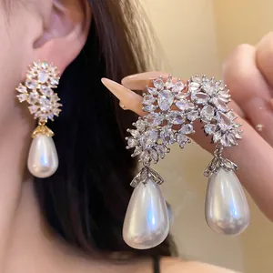 Primer plano detallado de pendientes largos con circonitas y perlas de gota en la modelo
