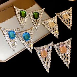 Close-up of geometric triangle earrings with colorful crystal centers and rhinestones