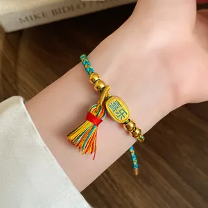 Handmade woven five-color rope bracelet with gold joy charm pendant shown in detail
