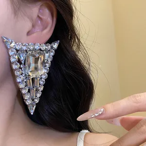 Close-up detail of luxury triangular stud earrings with large central crystal and rhinestones