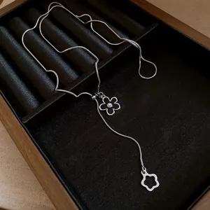 Macro detail of an elegant silver flower pendant necklace with pearl on black velvet lining