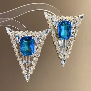 Detailed close-up of elegant triangular earrings with blue gems and clear rhinestones