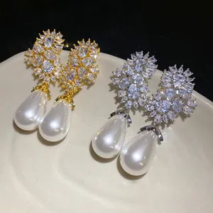 Primer plano de elegantes pendientes de perlas gota y circonitas brillantes en oro