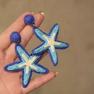 Gros plan sur des boucles d'oreilles étoile de mer bleues en tissu avec texture tressée.