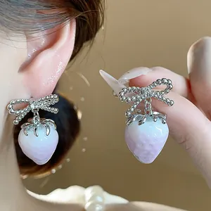Detailed close-up of sweet resin strawberry earrings featuring sparkling bow accents.