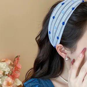 Elegante cerchietto largo in tessuto a righe blu e bianche con pois ricamati su modella.