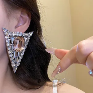 Close-up of elegant triangular crystal earrings with champagne center stone