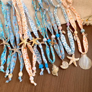 Close-up of ocean-themed scarf necklaces featuring seashell and starfish pendants for summer