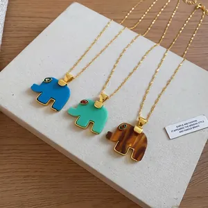 Resin elephant pendant necklaces with rhinestone eyes and gold chains on a display board