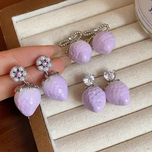 Close-up detail of lavender resin strawberry earrings with heart zircon and pearls.