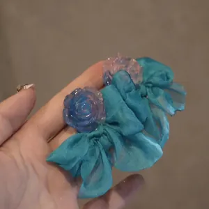 Vue macro détaillée de boucles d'oreilles en ruban bleu avec roses en résine élégantes