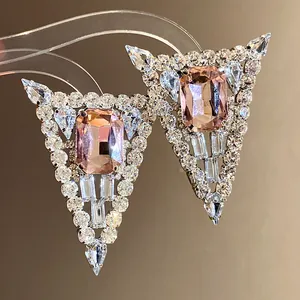 Close-up of geometric triangle stud earrings with pink crystal and clear rhinestones.