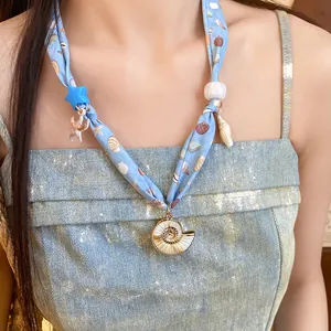 Detailed close-up of a blue beach scarf necklace with seashell and starfish charms.