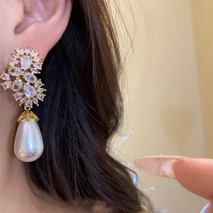 Vista detallada de elegantes pendientes colgantes con perla de gota y circonitas en la oreja