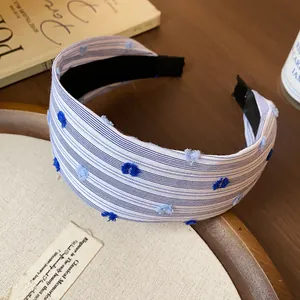 Dettaglio ravvicinato della fascia per capelli a righe blu e bianche con fiori in rilievo