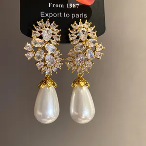 Primer plano de pendientes de perlas en forma de gota con racimos de circonitas