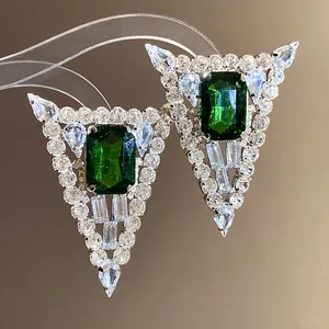Close-up of elegant triangle stud earrings featuring emerald green stone and crystal inlay