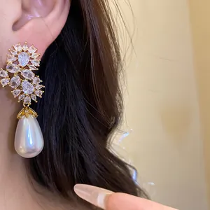 Primer plano detallado de un elegante pendiente de perla con racimos de circonitas en oreja.