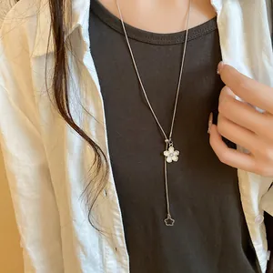 Close-up of a stylish white flower pendant pull-adjust necklace worn with a white linen shirt