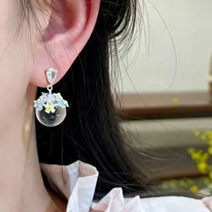 Elegant drip oil flower earrings with transparent ice-clear sphere drop on Asian model