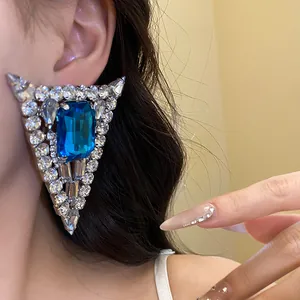 Detail shot of a large triangular rhinestone stud earring with a blue center stone