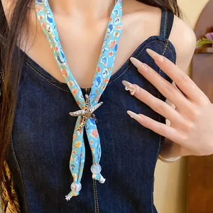 Close-up of ocean-themed blue scarf necklace with starfish pendant and marine patterns.