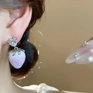 Detailed close-up showing heart zircon and lavender resin strawberry earring on model