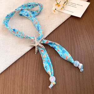 Close-up detail of an ocean-themed scarf necklace with a silver starfish pendant