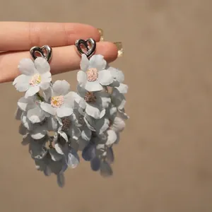 Vue macro détaillée montrant la texture des boucles d'oreilles fleur en tissu bleu clair