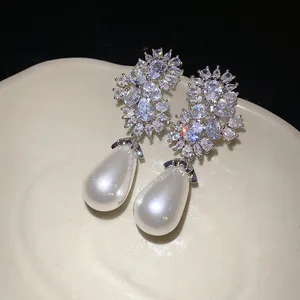 Primer plano de elegantes pendientes de perlas en gota con circonitas brillantes