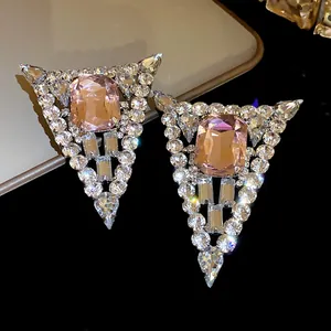 Macro view of triangular pink crystal earrings with sparkling diamond studs