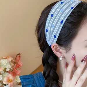 Dettaglio ravvicinato di un cerchietto in tessuto a righe blu con fiori ricamati su modella.